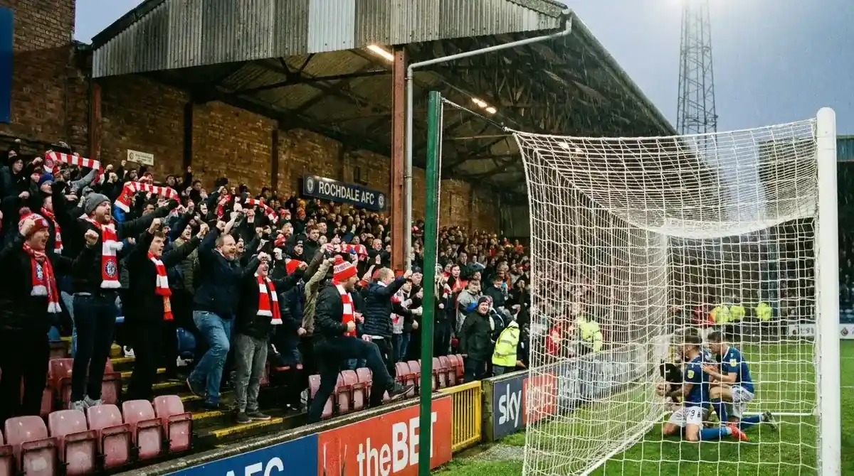 League One fans supporting home team behind goal at lower league ground