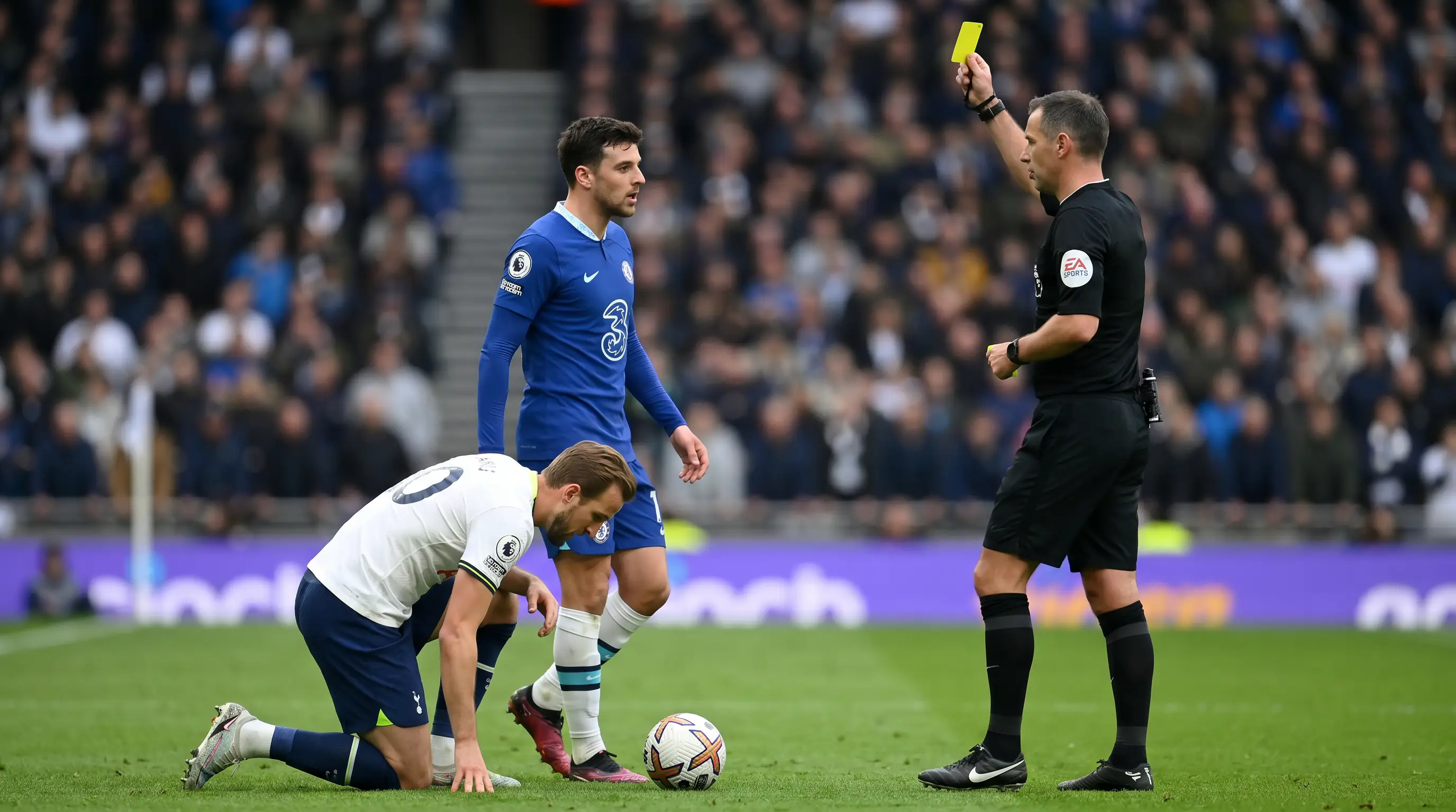 Referee issuing a yellow card after a heavy tackle in a Premier League match