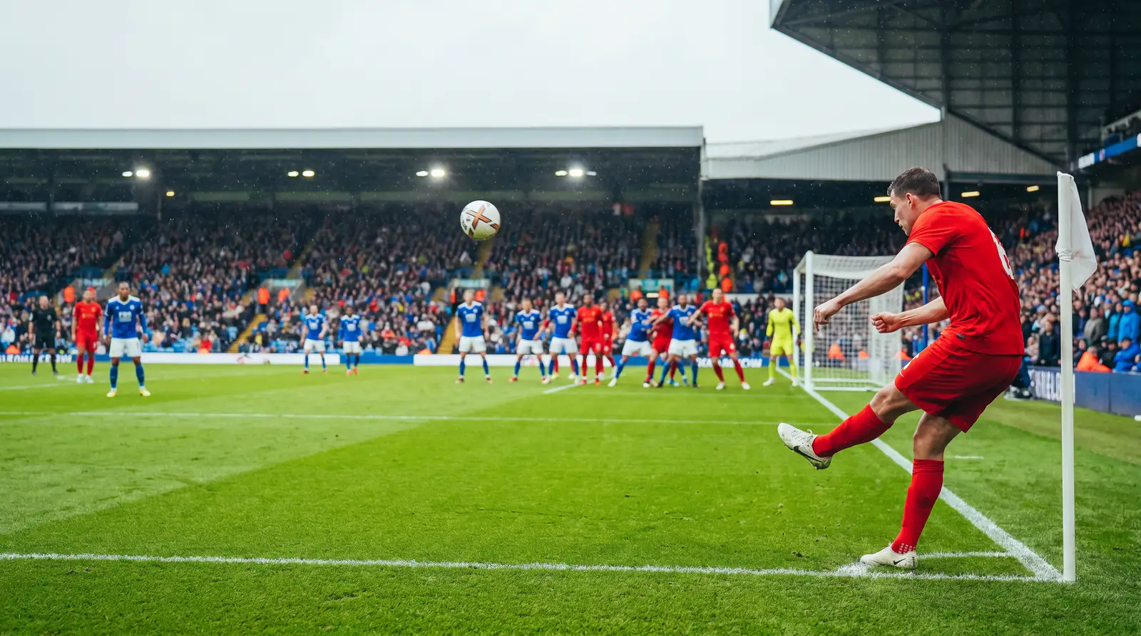 Football corner kick being delivered into the penalty area during a match
